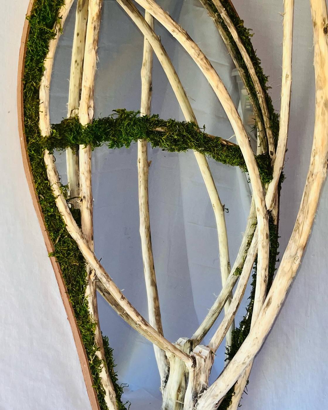 The finished mirror: an arched frame with mossed rim and a lattice of pale branches across the glass.